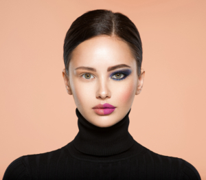 One half face of a beautiful white woman with bright makeup and the other is natural. Woman portrait with a deep blue eye makeup of one eye. Natural and vivid make-up on a female face. Fashion style